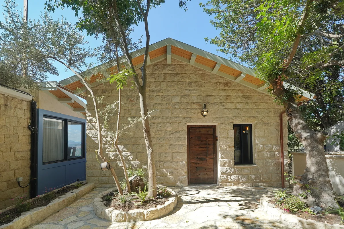 בית האבן מבחוץ, בין עצי הזית בחצר המרוצפת